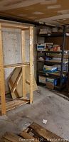 Wooden shelf and metal shelf in unfinished basement showing structure and stored items