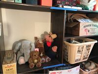 Shelf with four stuffed animals including an elephant, horse, bear, and pig, alongside a laundry basket and boxes.