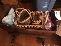 Wooden cradle with several woven baskets inside showing size and condition