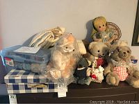 Photo showing collection of teddy bears, miniature dolls, and some folded curtains in the background