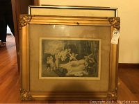 Framed painting with cherubs and reclining woman in brass-finished decorative frame.