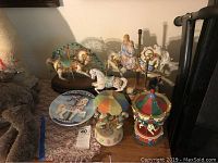 Seven carousel horse figurines and decorations displayed on a table, showing various sizes and designs.