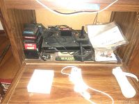 Atari 2600 console with joystick controllers, stacked game cartridges, and instruction manuals on wooden shelf