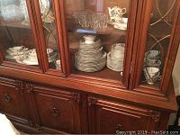 Wide view of china cabinet displaying complete service set with plates, bowls, teacups, and saucers in Prairie Rose pattern