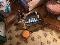 View of fireplace tools in stand, log holder, saddle-shaped bellows and bed warmer on a floral rug near furniture
