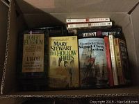 Box containing Robert Fulghum's Uh-Oh, Mary Stewart's The Hollow Hills, Alexander Kent's Signal Close Action!, and other novels.