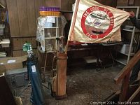 Photo of vintage golf clubs in brown and blue bags next to golf carts and a table, with a Navy flag displayed in the background.