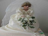 Full view of the Diana wedding doll sitting, showing the white gown with lace, veil, and bouquet.