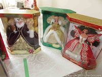 Three special edition holiday Barbies in original boxes on a table, showing overall lot condition and packaging