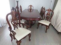 Six carved wood chairs with upholstered seats arranged around a dining table
