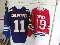 Front and back view of both jerseys hanging, showing Culpepper #11 Minnesota Vikings NFL jersey and Toews #19 Chicago Blackhawks NHL jersey