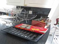 Overview of metal wire baskets, metal stand, grill pan, flour sifter, Ravioli Chef and Imperia noodle making machine in boxes on countertop