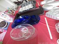Overview of muffin pans, glass and blue glass mixing bowls, wooden tray, and bakeware items on red tablecloth