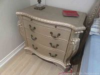 Full view of side table showing carved edges, three drawers, and metal handles.