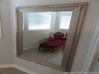 Full view of the large rectangular mirror showing reflective surface and frame against a wall.