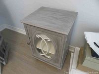 Angle view of the night stand showing the painted wood surface and decorative door front design