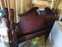 Side view of cherry wood poster bed headboard with carved posts.