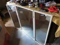 Tri-fold mirror fully opened, showing three rectangular mirror panels with laminate frame.