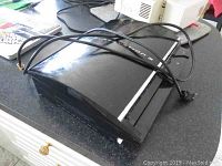 Side angled photo of PlayStation 3 console with visible power cord.