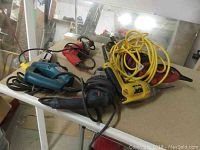 Photo showing a selection of power tools including Bosch hammer drill with yellow power cord, red Milwaukee Magnum hole shooter, Skil saw, and DeWalt drill.