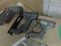 Three used grey Senco pneumatic staple guns side by side on a table, showing overall condition and brand