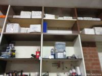 Wall-mounted shelving unit loaded with multiple white cardboard boxes of fasteners, a plastic case of anchors and a yellow DeWALT router tool.