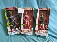 Three boxed Spice Girls dolls displayed upright on a blue background, showing all dolls and packaging fronts.