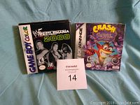 Photo showing both games together on light blue cloth background, game cases for Wrestlemania 2000 and unopened Crash Bandicoot 2