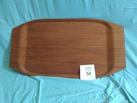 Full view of the rectangular teak tray on a blue cloth background, with the tray measuring around 24 by 12.5 inches.