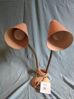 Front view of mid century double gooseneck lamp showing both adjustable cone-shaped shades and round base with light fixture bulbs visible.