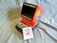 Full view of the Donkey Kong Junior Coleco arcade game unit on blue cloth backdrop, showing front screen and control panel with joystick and buttons.