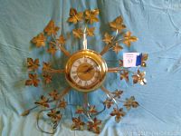 Full view of the starburst clock showing brass circular center and starburst leaf design extending outward