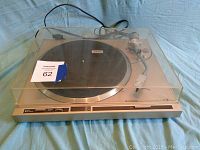 Pioneer PL-200 turntable with dust cover closed on a blue surface, showing whole unit with power cord.