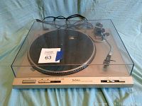 Technics SL-D202 turntable with clear dust cover closed showing front control panel and tonearm.