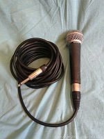 Full view of Shure SM58 microphone with coiled XLR cable attached, cable end visible
