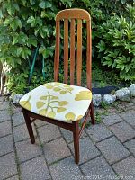 Front angle view of the teak chair showing side and seat upholstery.
