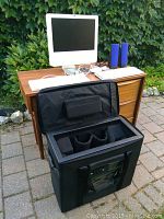 White iMac on wooden desk with keyboard, mouse and blue speakers plus black Tenba case in foreground