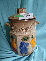 Full front view of the Scheurich Rumtopf pottery jar, showing the overall shape, lid, and colorful fruit motifs on the body.