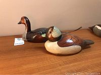 Two hand crafted wood birds, pintail and bufflehead by D.R. Jackson displayed on wooden surface.