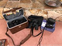 View of all items including binoculars with case, cameras, camera lenses, and cables in boxes