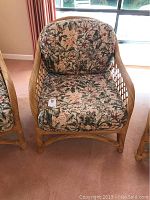 Front view of the wicker chair with floral cushions, showing seat and backrest cushion clearly.