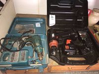 Both drill sets shown side by side on wooden surface. Left is Black and Decker corded drill in blue case, right is Makita 12V cordless drill in black case.