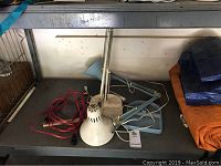 Two white adjustable desk work lights with heavy bases and red cords on a gray table.