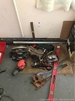 Tools assorted on the floor including hand saws, levels, rulers, skill saw, and jigsaw.