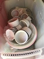 Photo showing assortment of small white round bowls, ramekins, and plates stacked inside a plastic container.