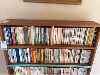 Full view of both shelves on wooden bookshelf filled with novels and books.