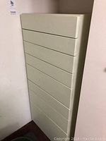 Full view of tall white wood cabinet with 8 drawers, showing its slim profile and minimalist design.