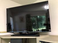 Front view of Sony 32 inch TV on stand in room setting.