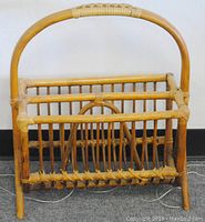 Front view of the natural rattan magazine holder showing its sturdy construction and open slatted design.