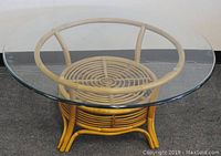 Full view of the round glass top rattan coffee table showing the glass and rattan base structure.